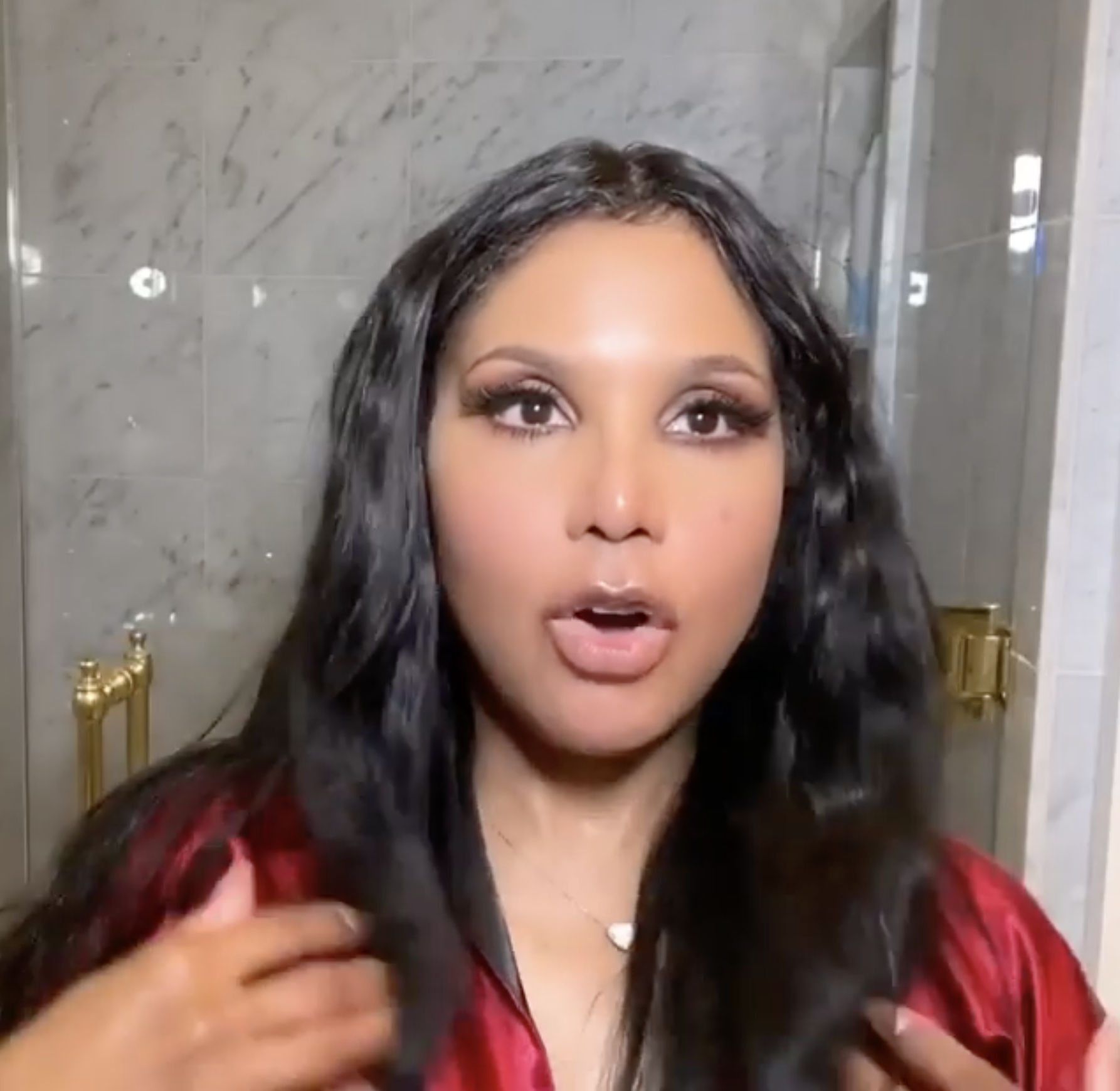 Toni Braxton wearing makeup, eyelashes, lip gloss and a red robe