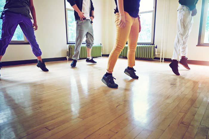 Multiple people are in a dance class, learning the next move.