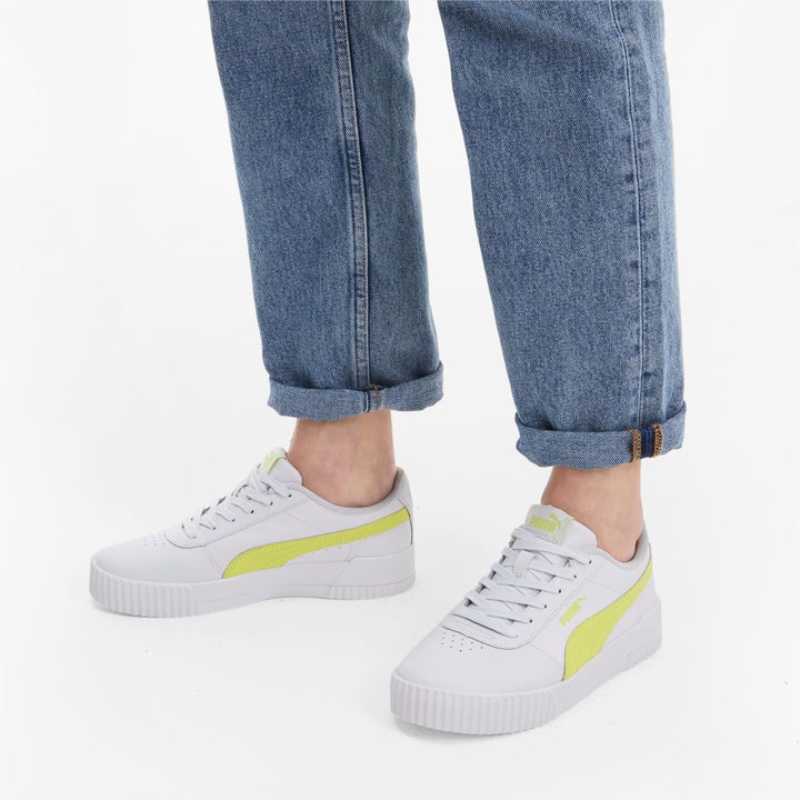 a model wearing white sneakers with yellow accents