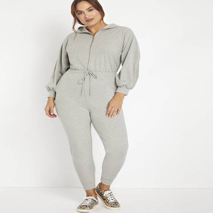 Model in the hooded sweatpants-material jumpsuit with drawstring waist