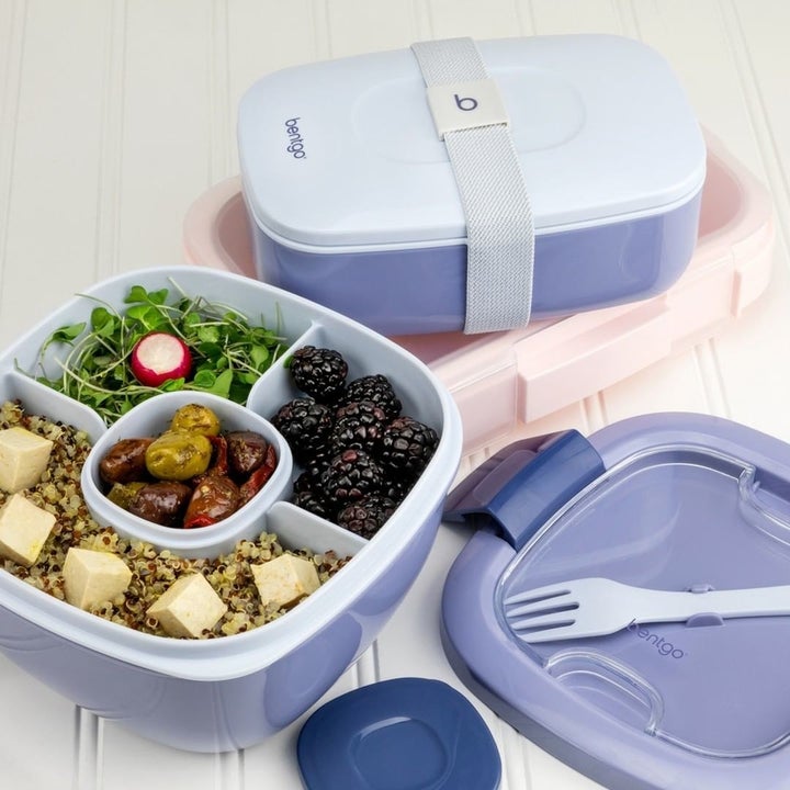 The container with its compartments filled with greens and fruits