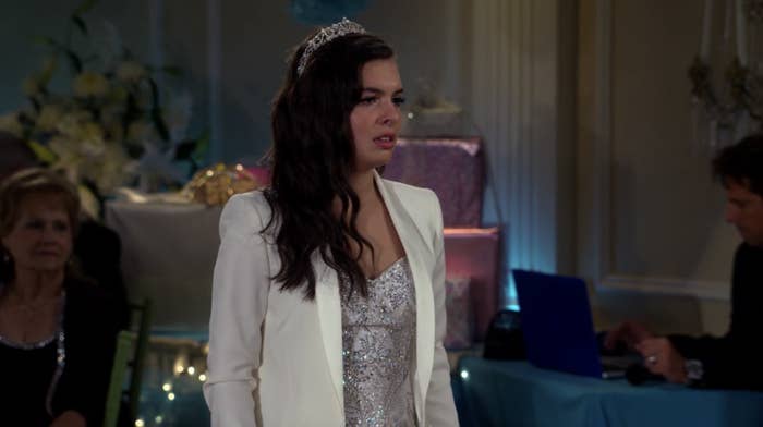 Elena Alvarez stands at her Quinceñera in a white suit and tiara.