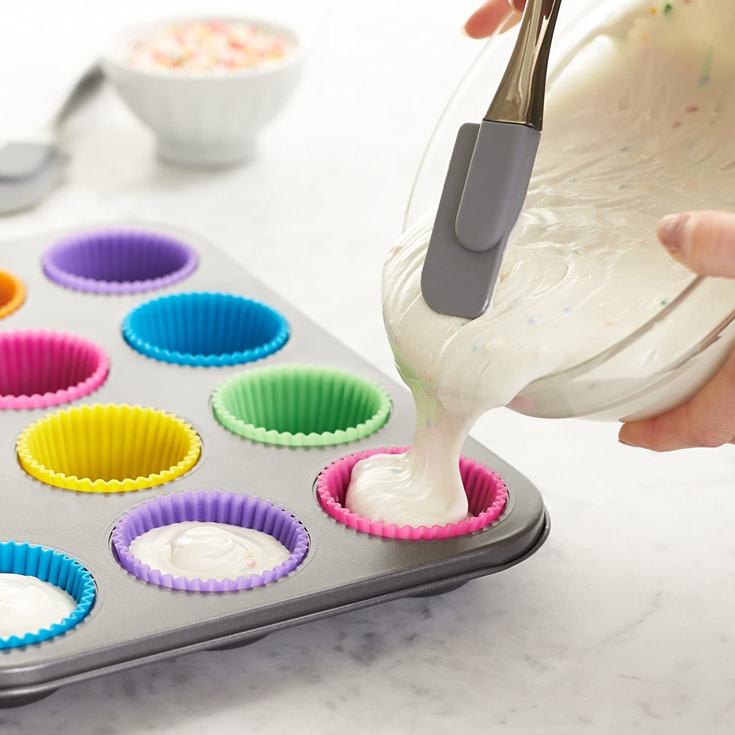 A person pouring batter into the silicone cups