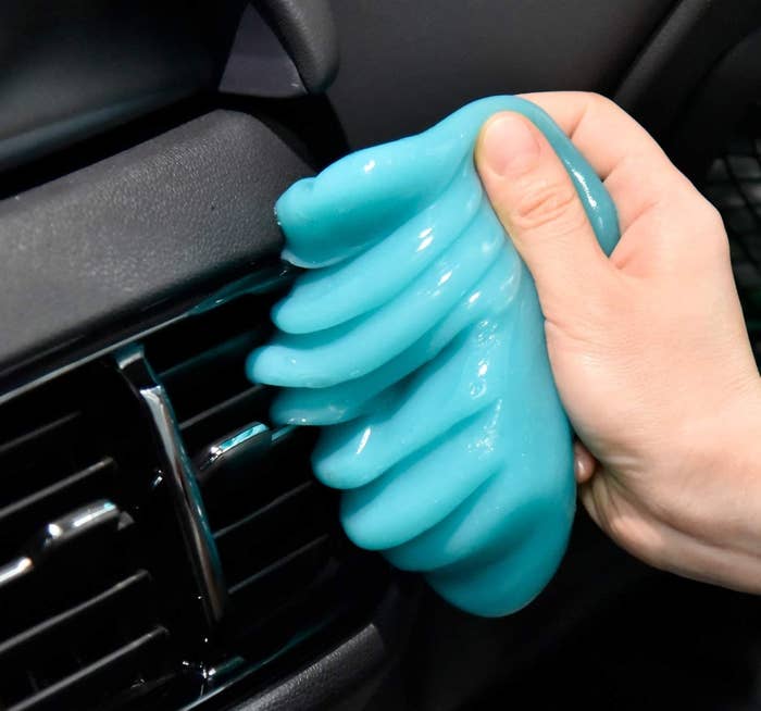 A person using the cleaning putty to peel dust off their car vents