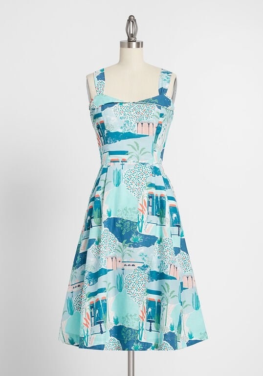 The blue, teal, white, and coral sleeveless dress printed with buildings and plants