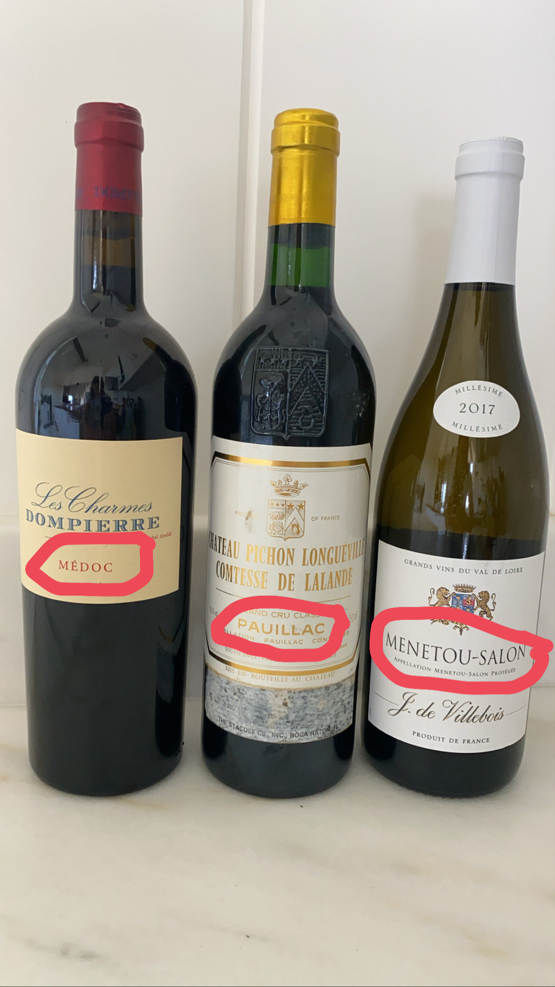 Three bottles of wine from France with their appellation (AOC) circled in pink.