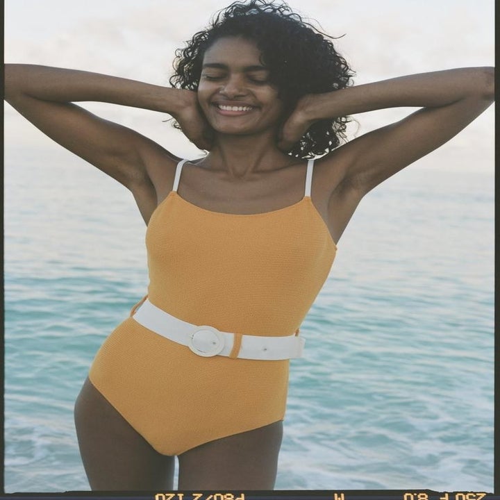 Model in yellow one piece with white belt