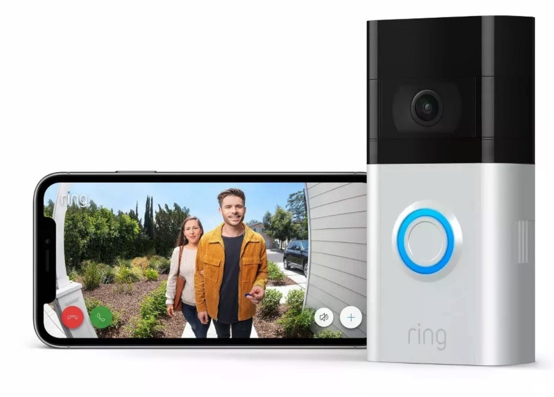 A Ring doorbell with a camera next to an iPhone displaying an image of two people with communication buttons at the bottom of the screen.