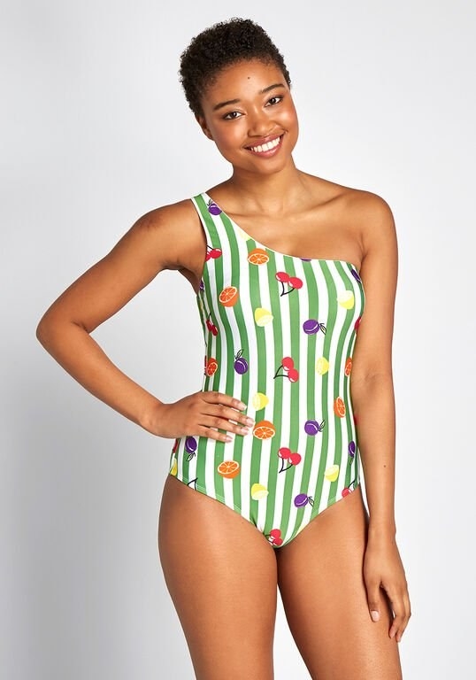 A model wearing the suit printed with white and green vertical stripes and plums, cherries, lemons, and oranges