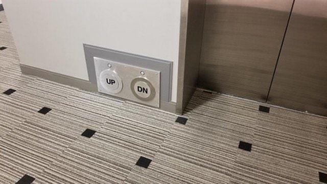 Large up and down buttons on the wall down by the floor next to an elevator door