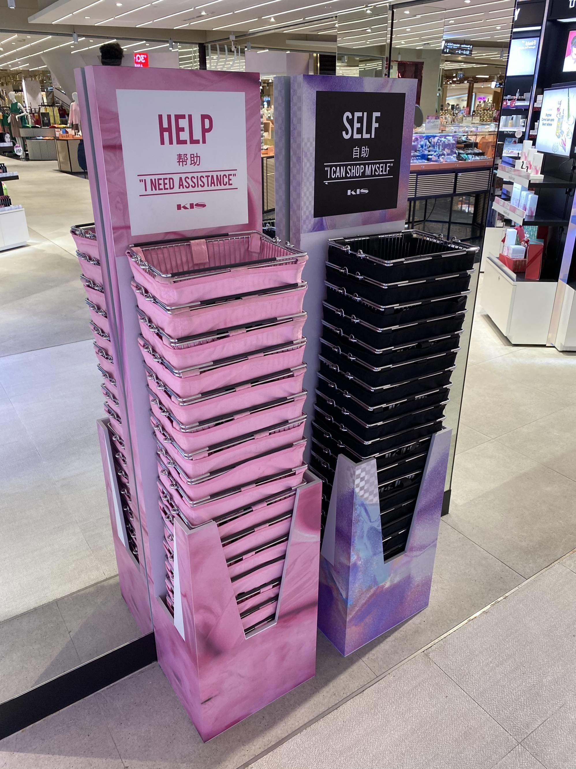 Pink shopping baskets that say I need assistance and black baskets that say I can shop myself