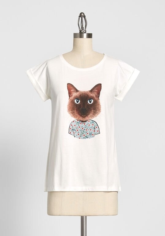 The white tee with an illustration on the front of a brown siamese cat who&#x27;s wearing a blue and orange floral-print tee 