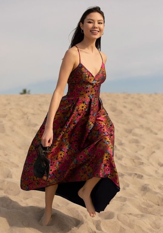 A model wearing the spaghetti strap pink, black, blue, and yellow brocade floral dress