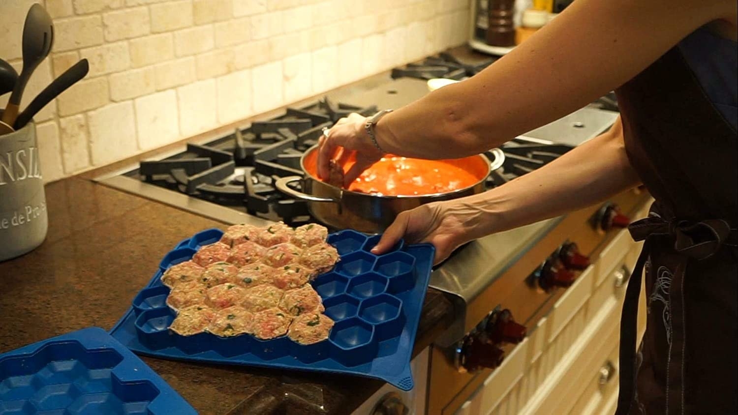 A person removes meatballs from the silicone mould