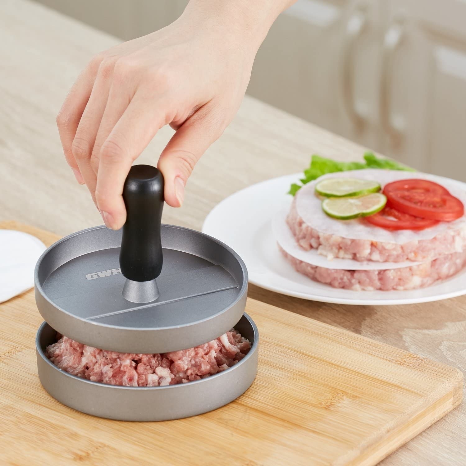 A person using the top tamper to press down the ground meat