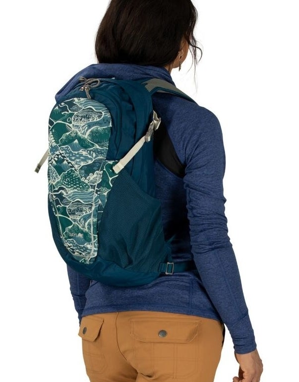 model wearing teal backpack with a mountain print on the outer pokcet