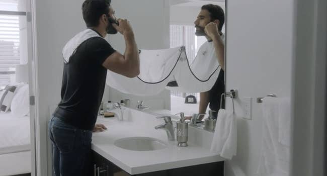 A model trimming their beard over a plastic 