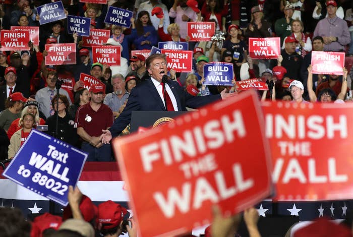 Photo of a Trump rally with people holding signs that say &quot;FINISH THE WALL&quot;