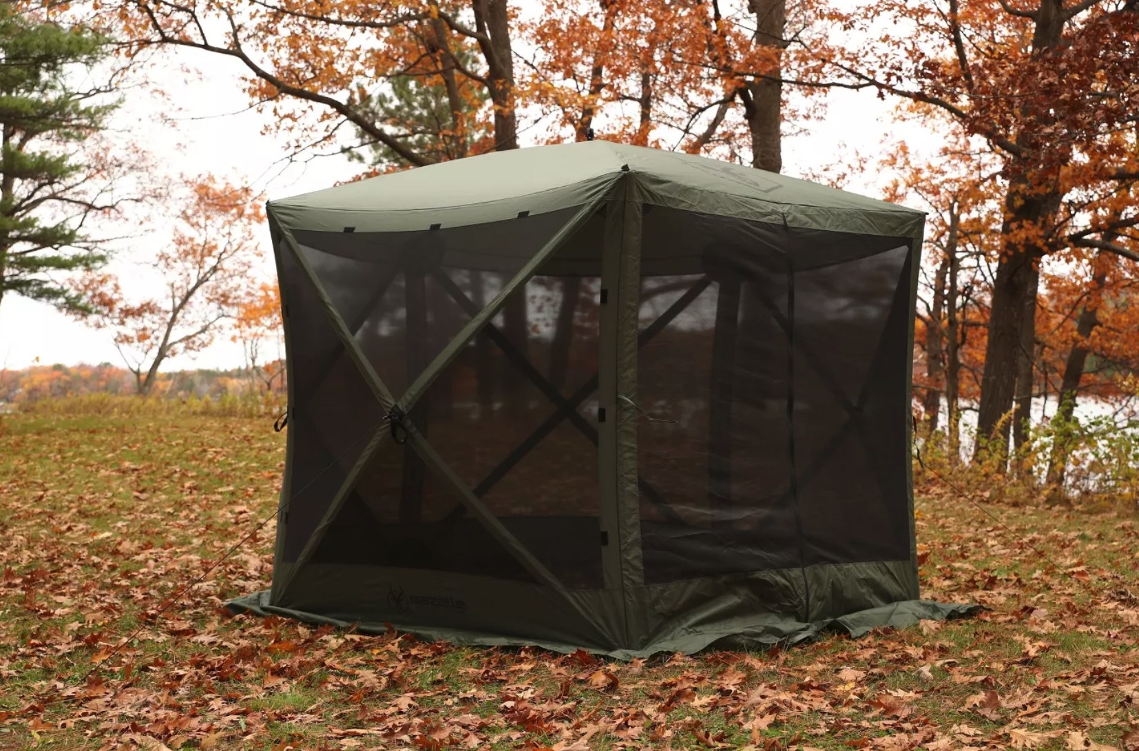 A large green tent with black screens in a field.