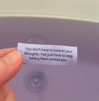 A person holding one of the messages that comes inside the bath bomb that reads 