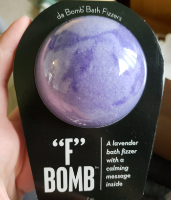 A reviewer holding the purple tie dye bath bomb