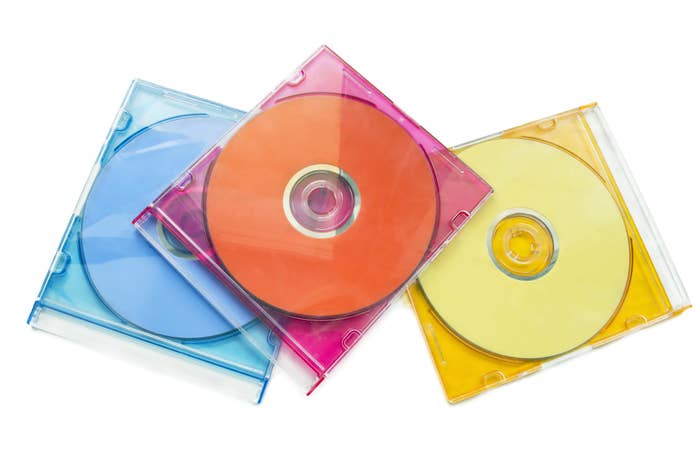 Three CD clear skinny jewel cases (one blue, hot pink, and yellow) with CDs inside them.