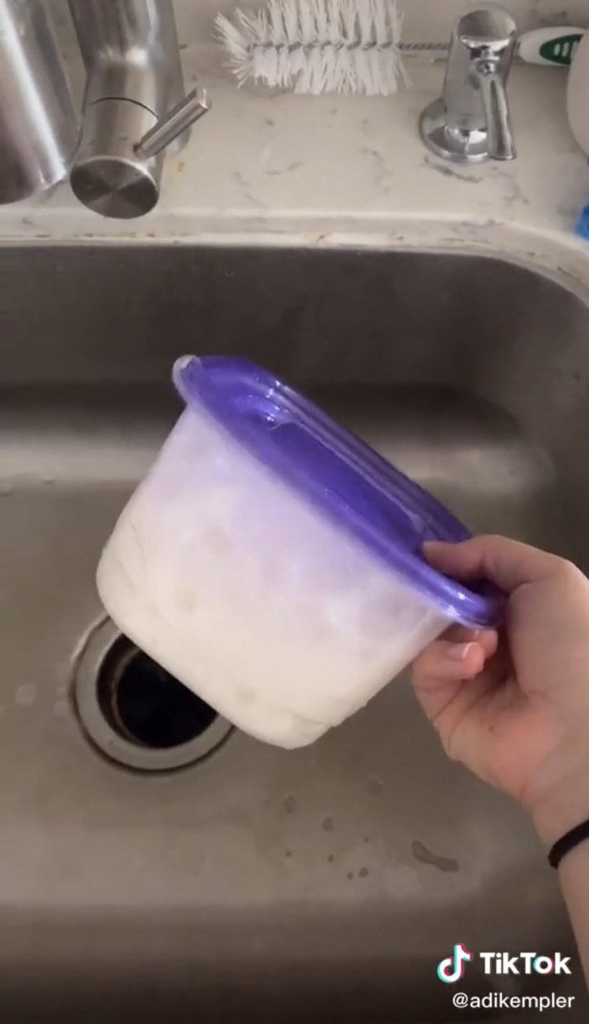 Screenshot of a woman&#x27;s hand shaking a tupperware container