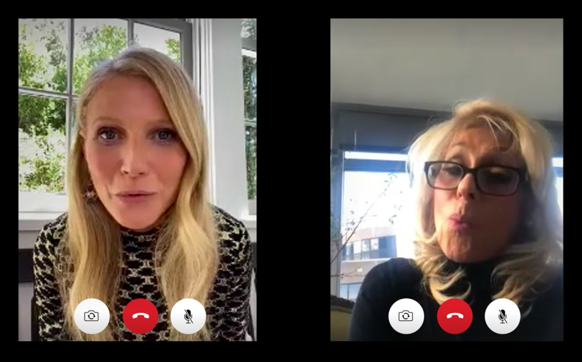 A still from The Politician showing Georgina and Dede both on Facetime talking to one another. Georgina wears a blue blouse and sits in front of a window while Dede wears glasses and a turtleneck. The phones show three icons for hang up, mute, and camera