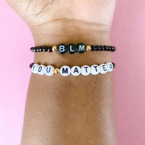 a model wearing a beaded BLM bracelet and another beaded bracelet that says you matter