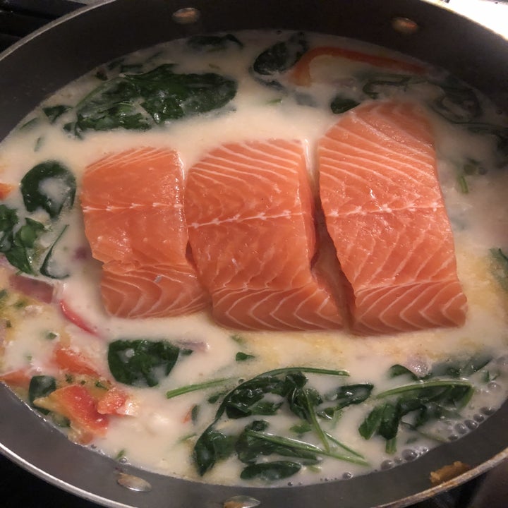 Salmon cooking in coconut milk with spinach.