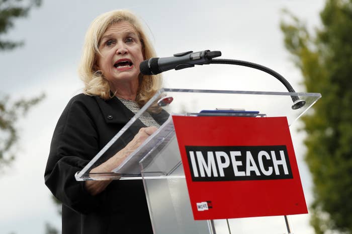 Representative Carolyn Maloney speaks at a podium with the word &quot;Impeach&quot; written on it