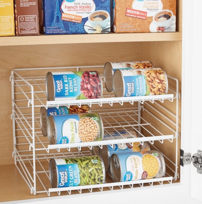 Three white wire-frame shelves holding various cans of food