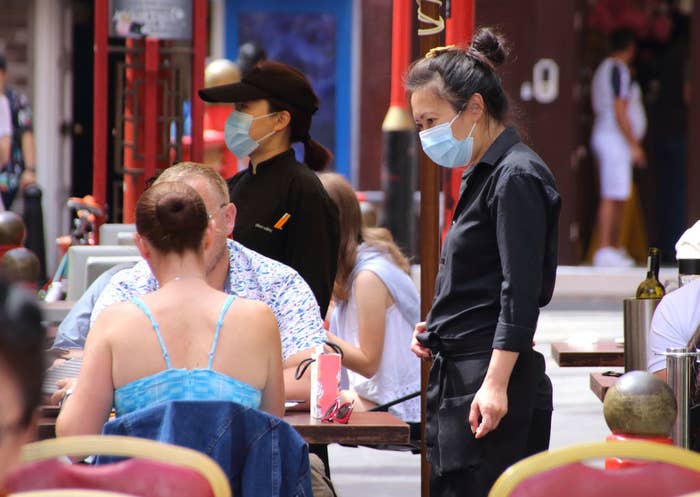 Server wearing a mask serves two people outside