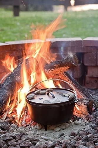 The Dutch oven sitting on top of coals in a blazing fire