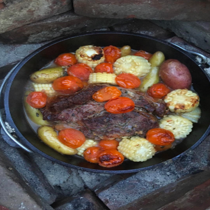 A review image of meat, corn, potatoes, and other vegetables being cooked in the Dutch oven