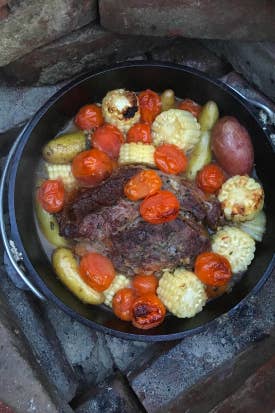 A review image of meat, corn, potatoes, and other vegetables being cooked in the Dutch oven