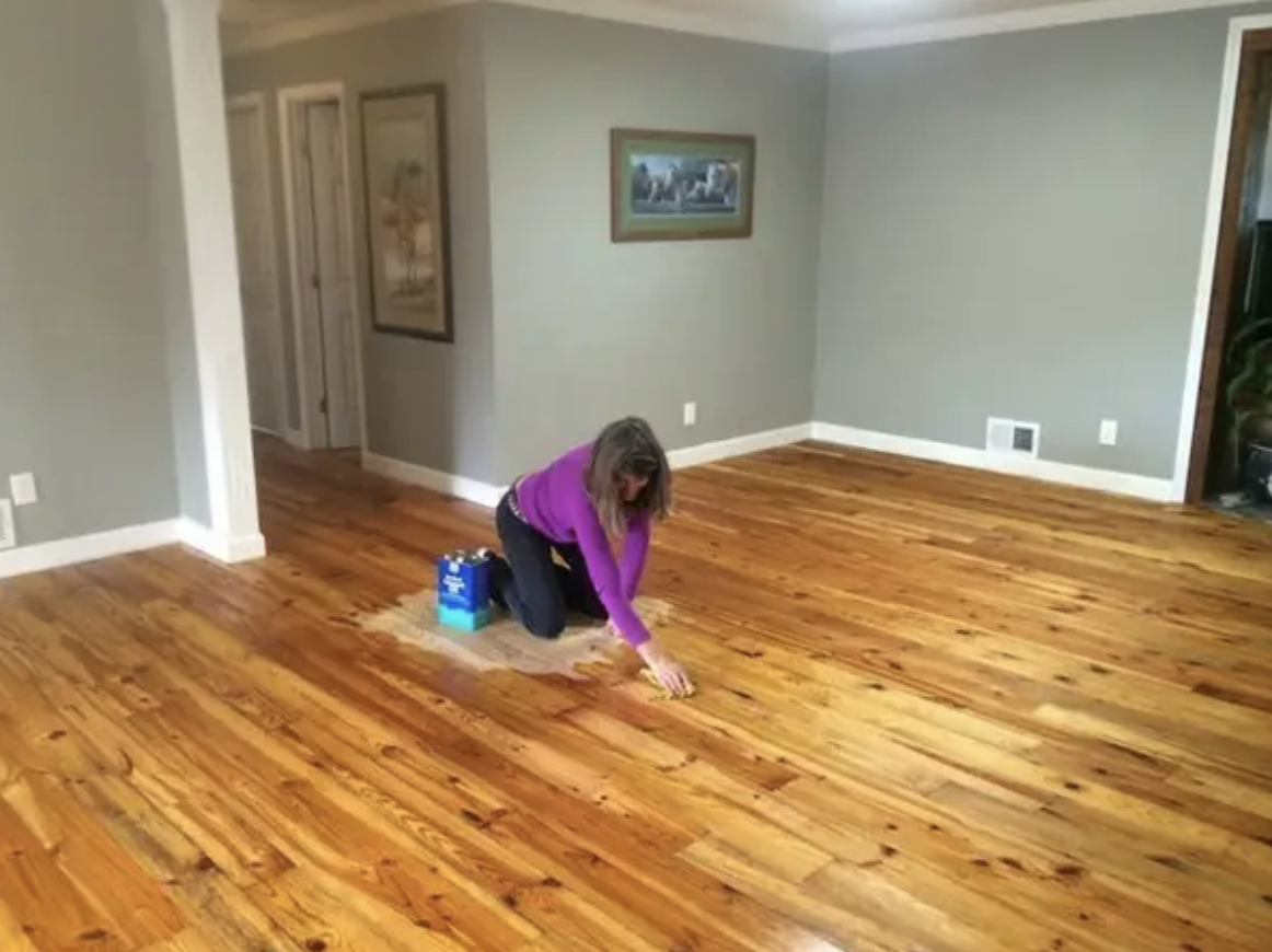 woman sitting on the only unpolished part of a freshly polished wood floor