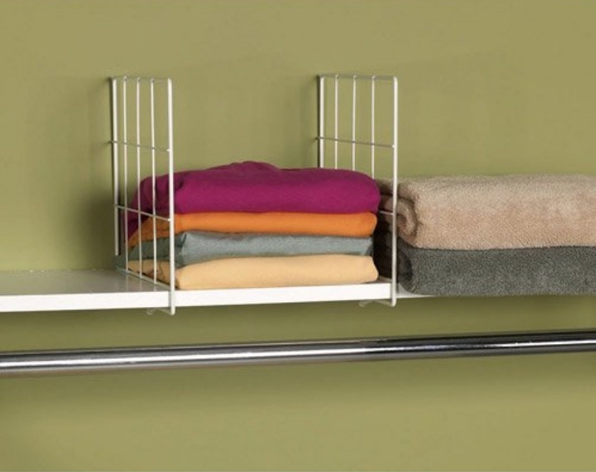 White wire-frame shelf divider with colorful folded t-shirts stored within