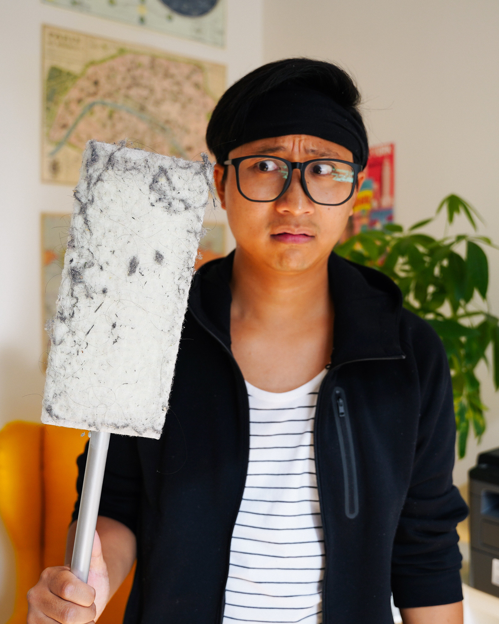 A man holding a dirty Swiffer with a disgusted look on his face.