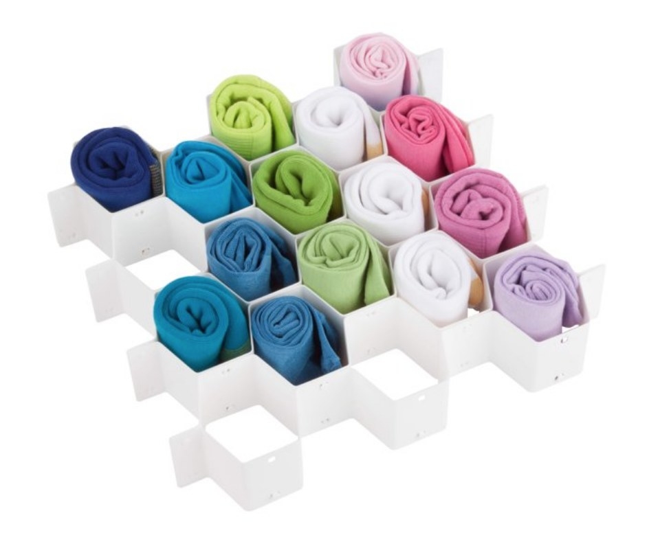 A white drawer sock organizer filled with multi-colored rolled up socks