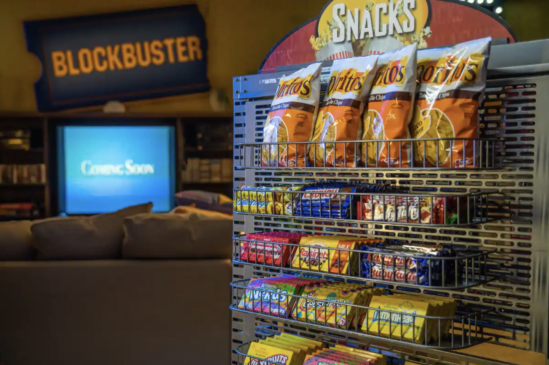 A rack filled with snacks like candy and chips next to the couch