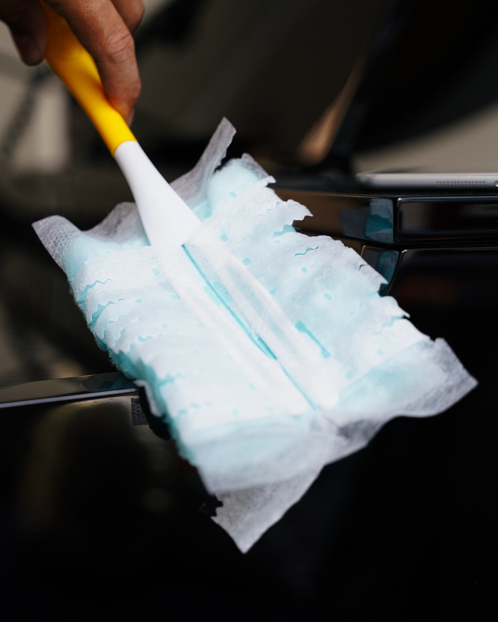 A close up of Swiffer duster that&#x27;s being used on a shiny piano.