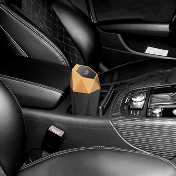 The mini trash can with geometric design sitting in the car's cup holders 