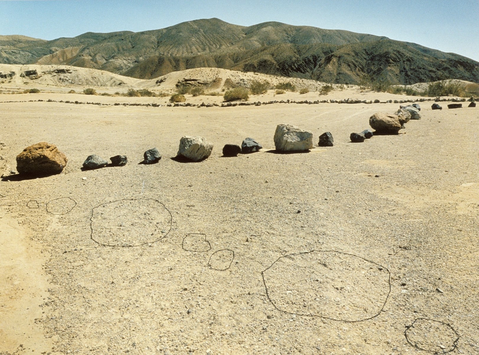 A line of boulders is seen next to a line of outlined boulders