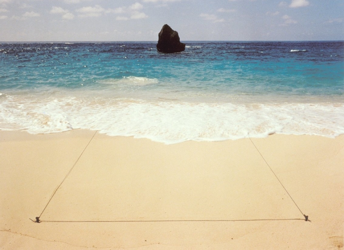 Waves wash away a triangle made in the sand