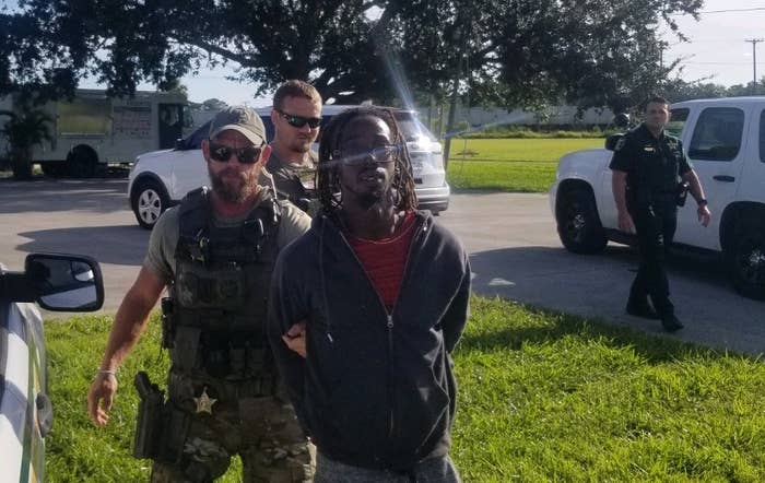 Two deputies lead a man in handcuffs toward a patrol car.