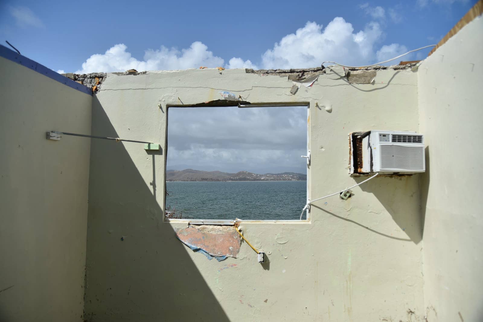 The wall of a house with no roof looks out onto the sea