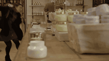 a gif of an actress from broad city smelling a row of candles