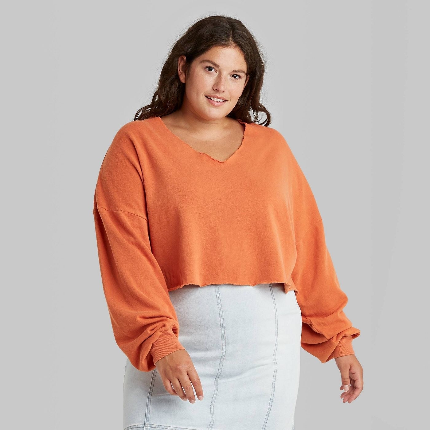 model wearing the cropped orange crewneck sweatshirt