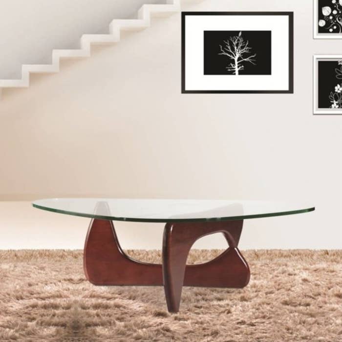 The large glass-topped coffee table with geometric wooden legs
